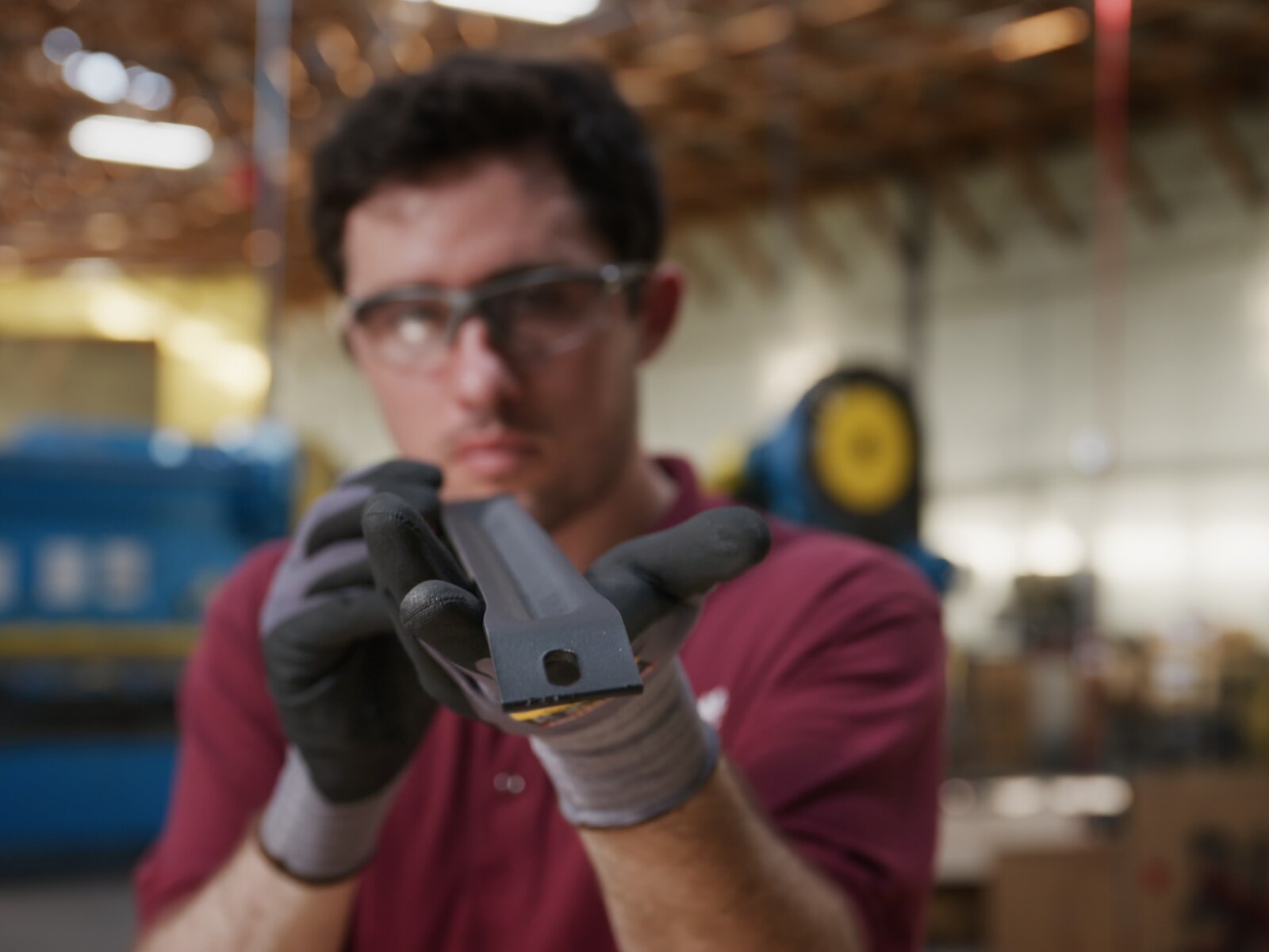 A Scenic Road craftsman inspecting a powder-coated steel side brace on the shop floor in Denver, Pennsylvania